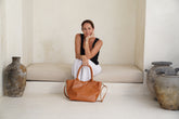 Paris Caramel leather tote handheld by woman seated.