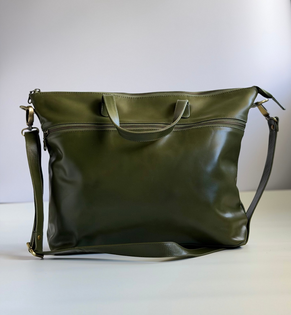 Green leather handbag on a white surface with a light gray background