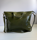 Green leather handbag on a white surface with a light gray background