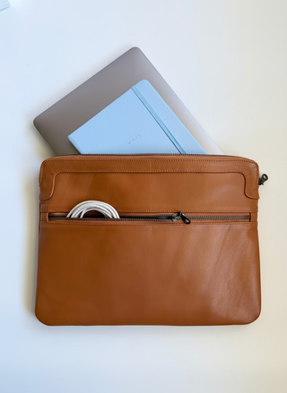 Caramel brown leather pouch with a laptop and notebook inside on a white background